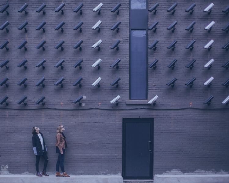 Two women looking up in front of a wall of security cameras